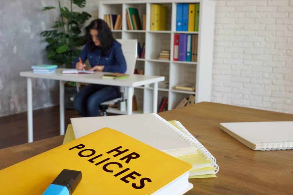 HR policies book on desk with employee in background
