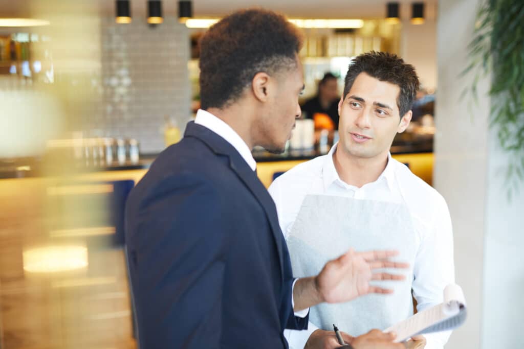 A restaurant manager has a conversation with a member of the waitstaff.